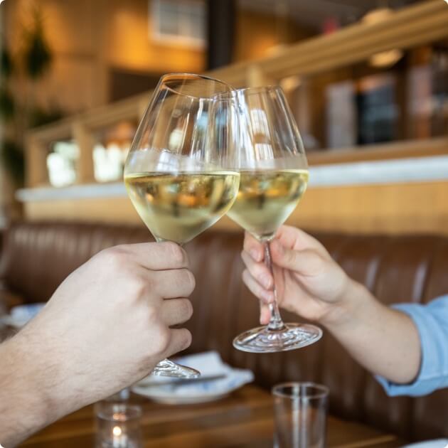 Two people clinking wine glasses together
