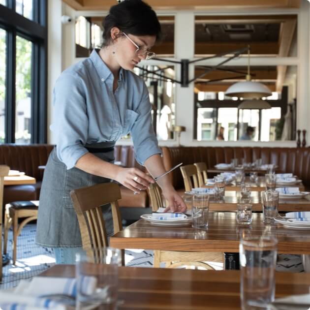Person setting up a restaurant table