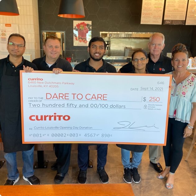 Group of people smiling with a large donation check