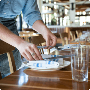 Person setting up a table in a restaurant