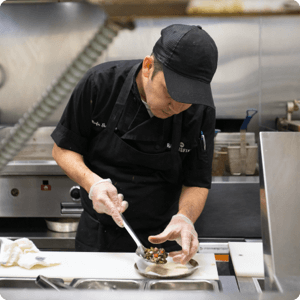Person plating a dish in a restaurant kitchen